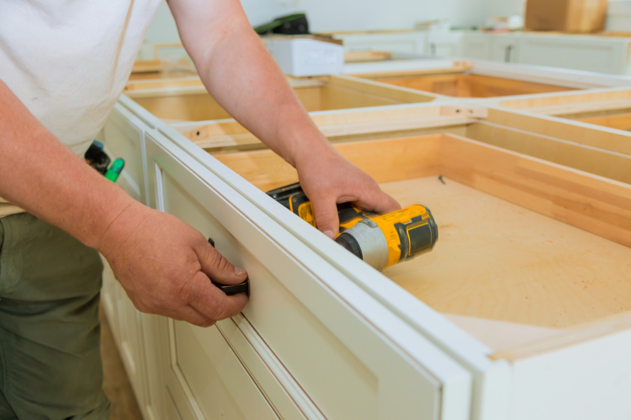 Close-up of a professional assembling a custom kitchen cabinet with a drill, showcasing reliable kitchen cabinet makers near you.