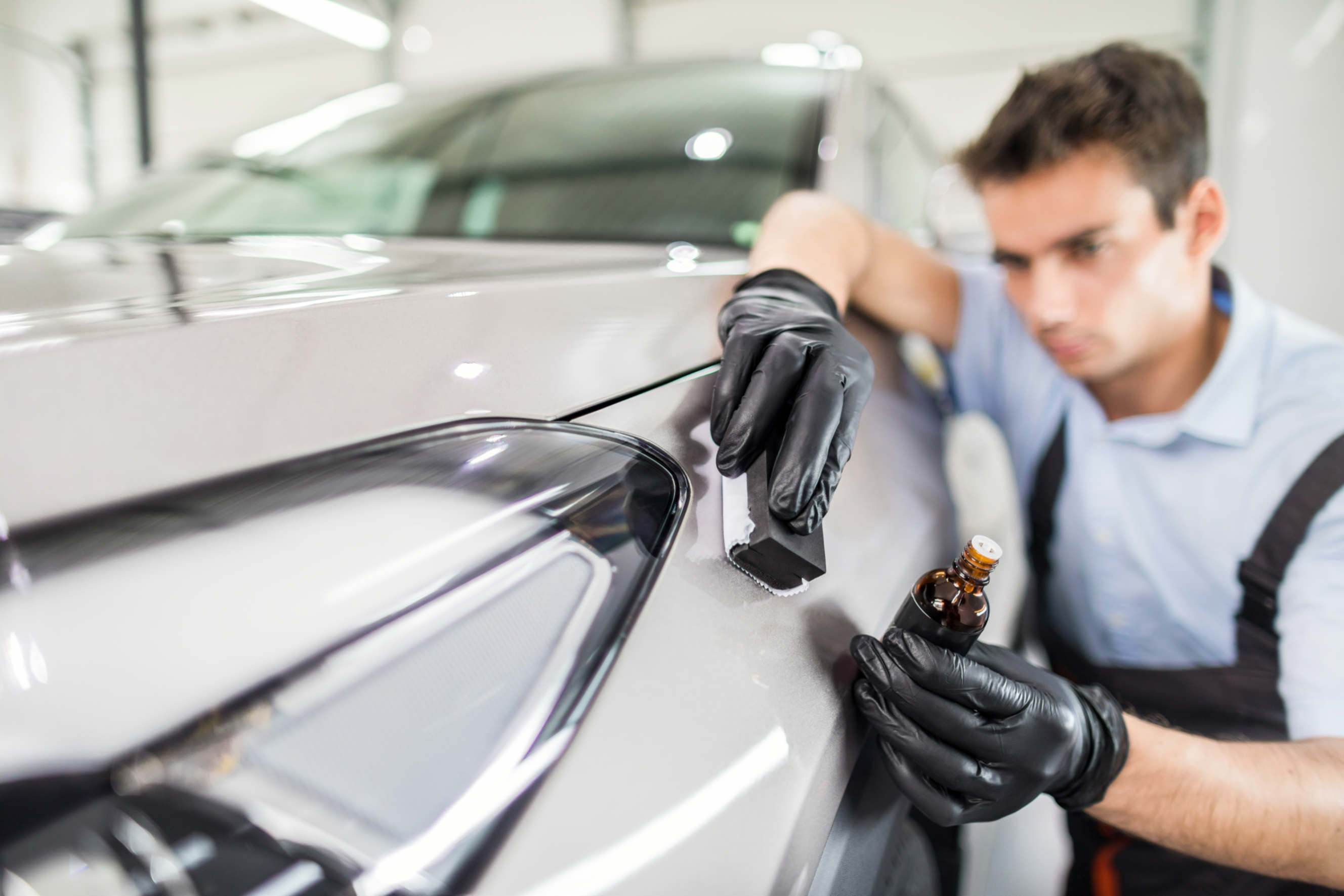 An expert applying PPF or ceramic coating for car paint protection.