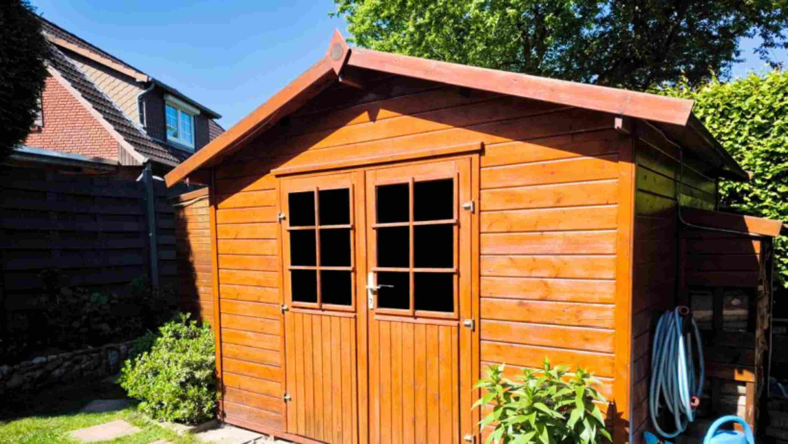 How to insulate a shed - A wooden garden shed with double doors and window panels, located in a sunny backyard surrounded by greenery