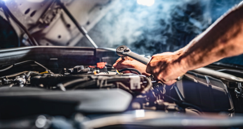 timing belt replacement cost - Mechanic at work fixing a car engine