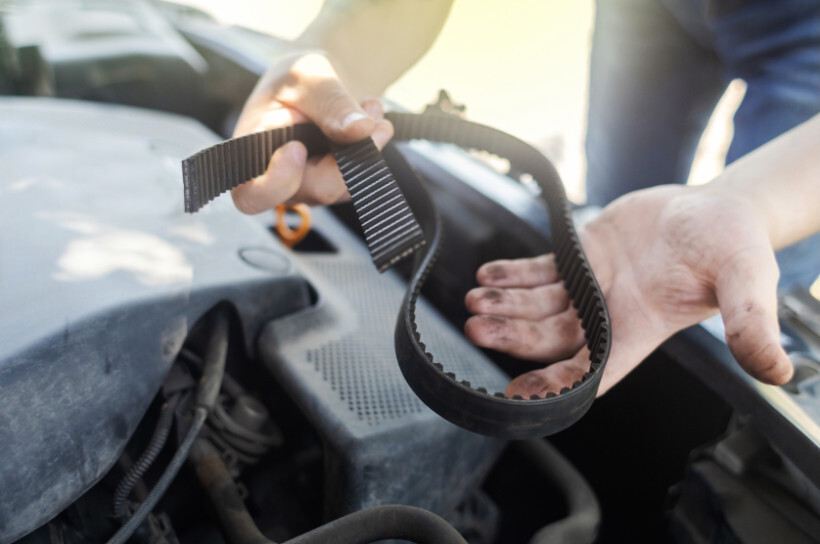 timing belt replacement cost - Mechanic holding a timing belt, ready for installation