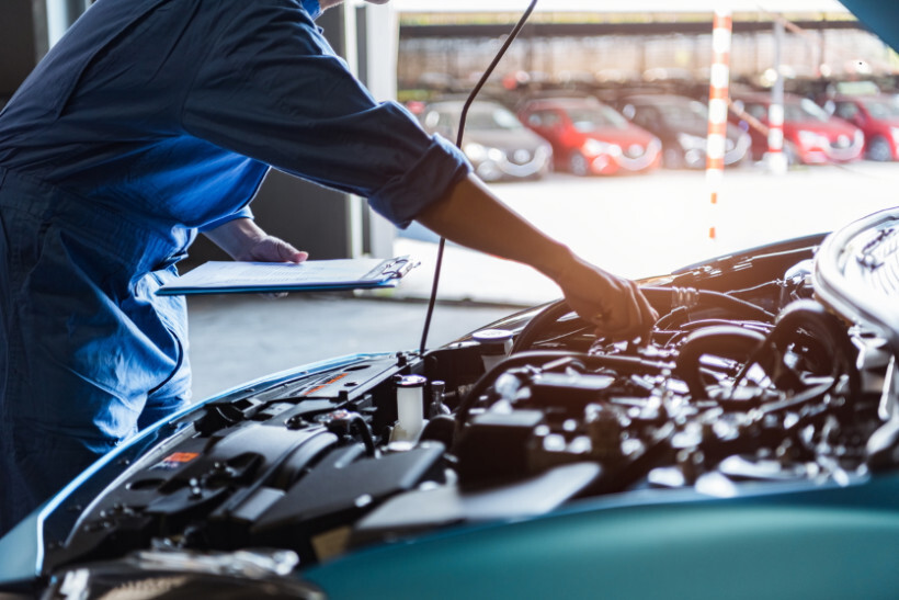 timing belt replacement cost - Mechanic fixing a car engine in a garage setting