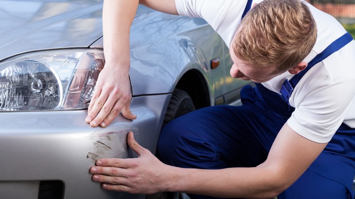 A technician inspecting a car bumper for damage during a car bumper repair near you. 