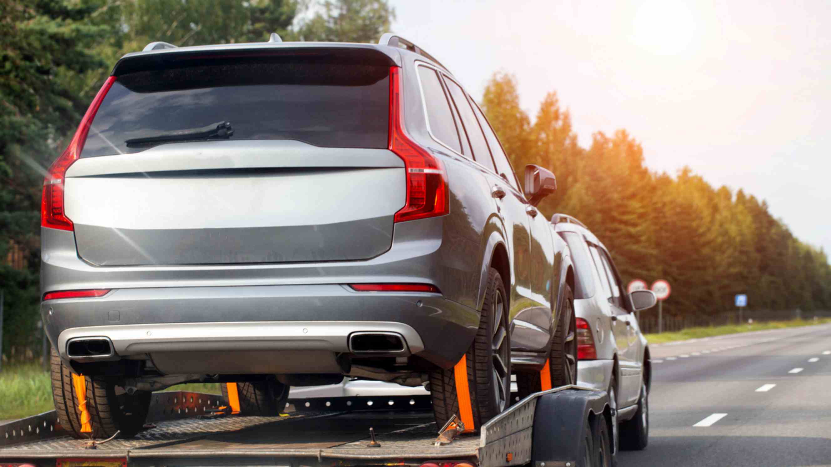 A silver SUV being transported on a flatbed truck as part of a car delivery service near you. 