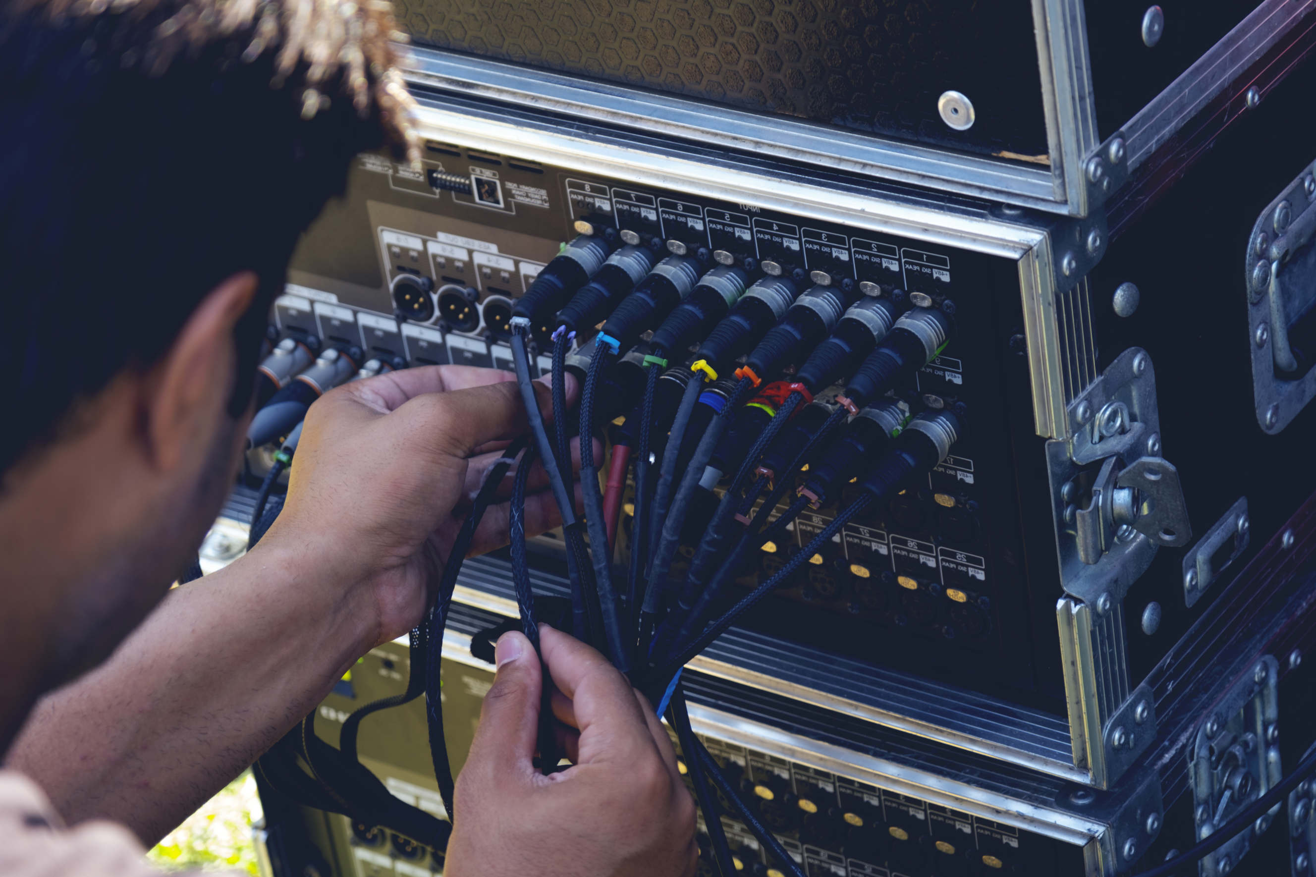 A technician working on a sound system amplifier, reconnecting wires and components.