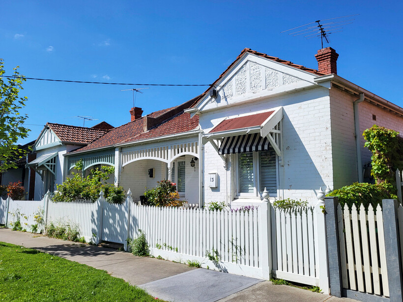 Single-storey houses with white picket fences and red tile roofs. - house vs flat