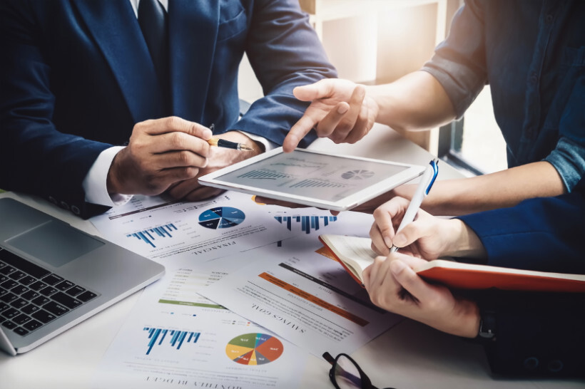 advisory-vs-consulting – close-up of businesspeople reviewing charts and financial reports on a tablet