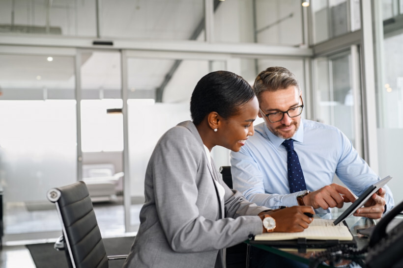 advisory-vs-consulting – woman taking notes while advisor explains insights on a digital tablet
