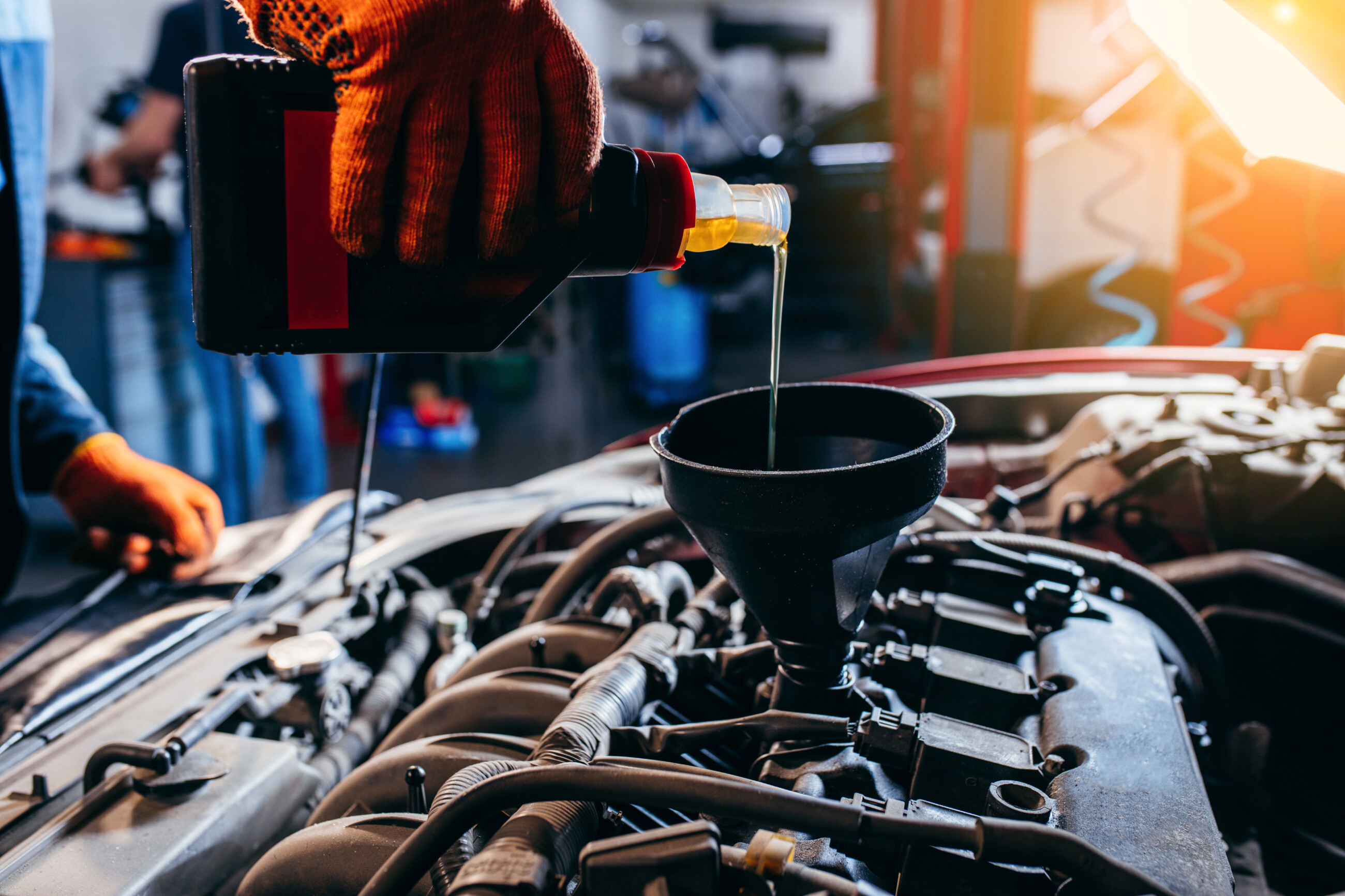 A mechanic pouring oil into the engine during an oil and filter change service near you.