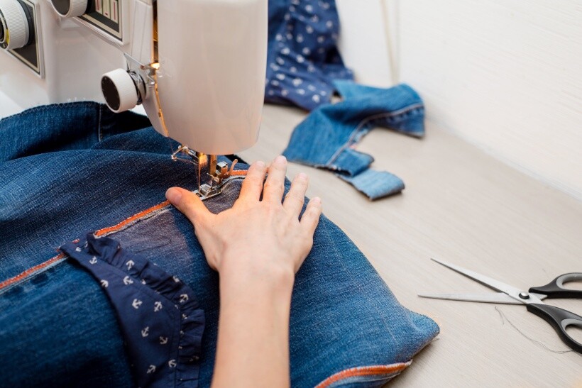 Alterations cost - ewing machine stitching denim fabric during a clothing alteration.