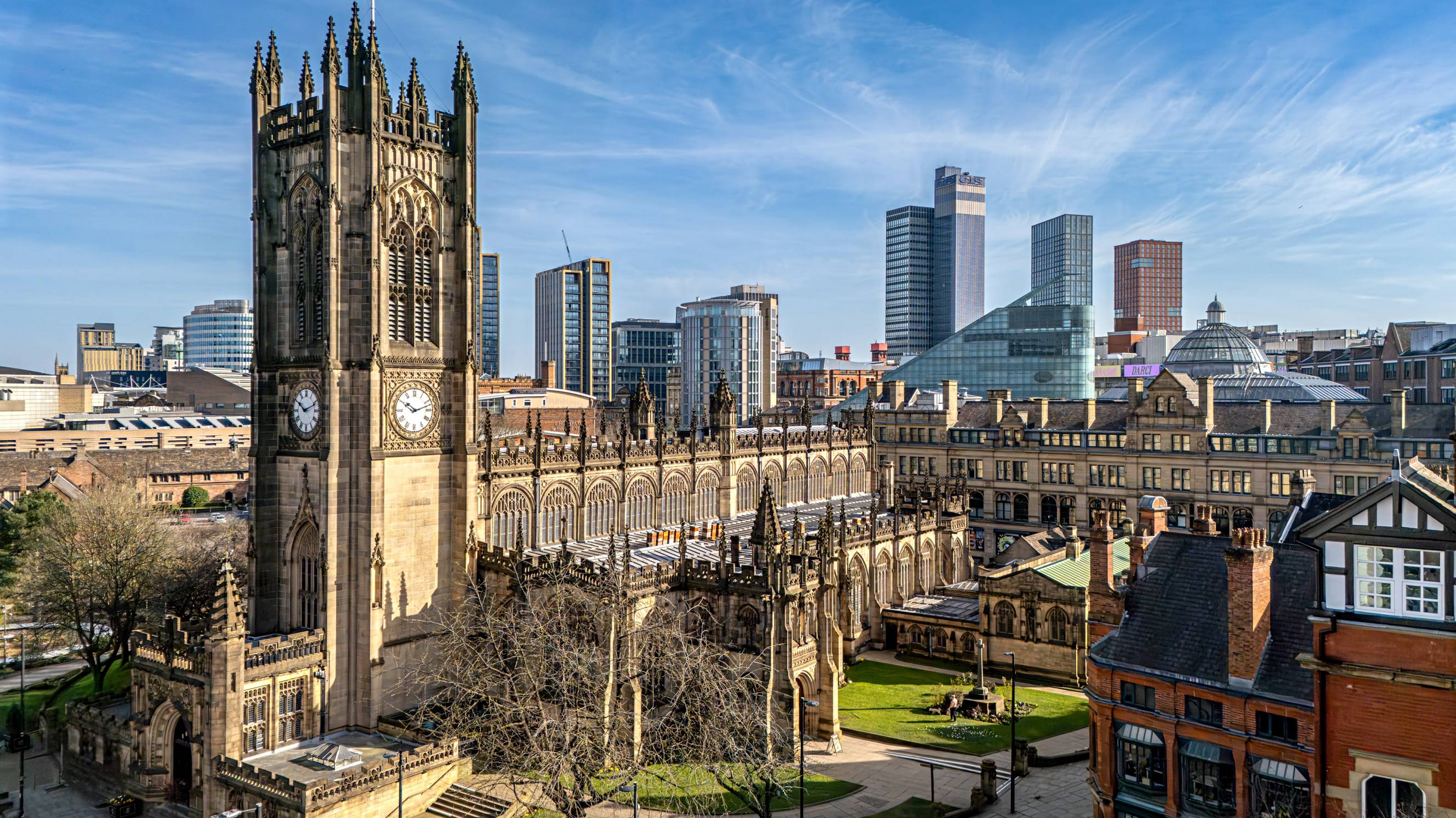 Historic Manchester Cathedral surrounded by urban architecture under a clear blue sky