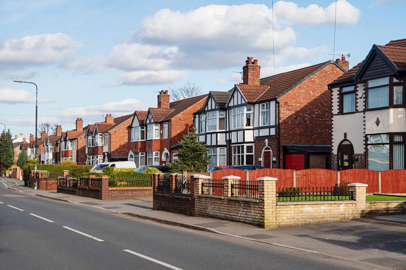 Quiet residential area with driveways and gardens, showing typical housing for people moving to Manchester