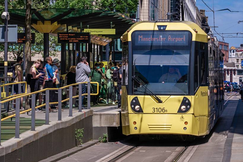 Metrolink tram at a city center stop, showcasing public transport options for those moving to Manchester