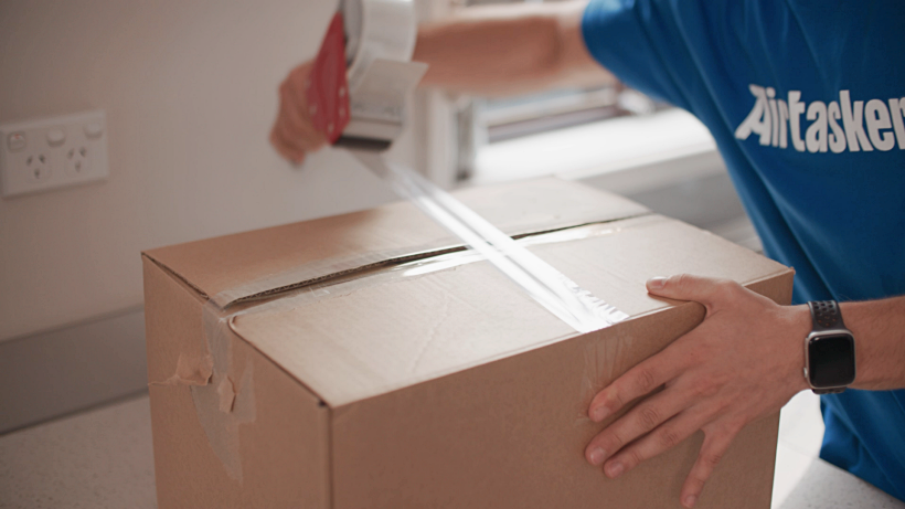 Tasker taping a box shut as part of the moving process to a new home in Liverpool