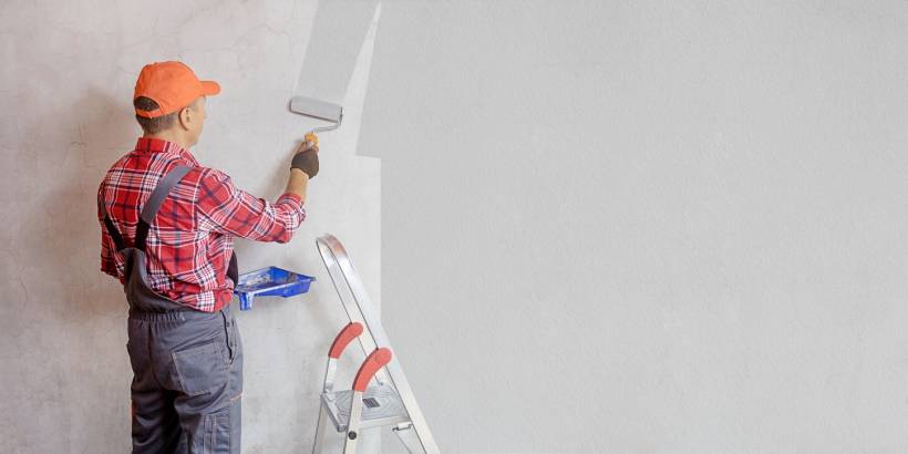 Dulux Warm Pewter vs Chic Shadow - Painter applying grey wall paint, possibly Dulux Warm Pewter or Chic Shadow