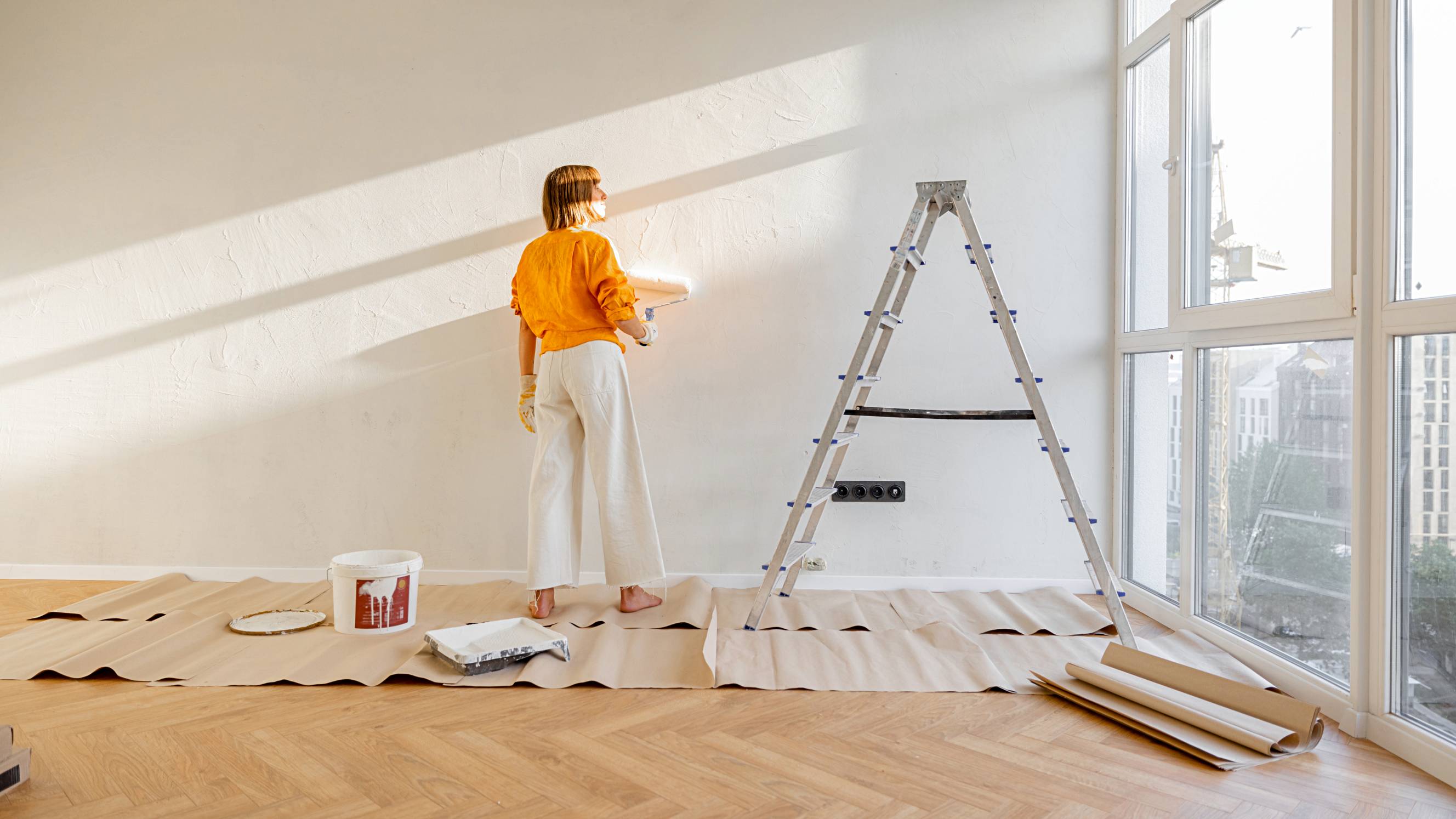 Woman painting a wall white, renovating her flat