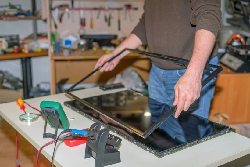 Technician disassembling a TV to assess potential repair costs