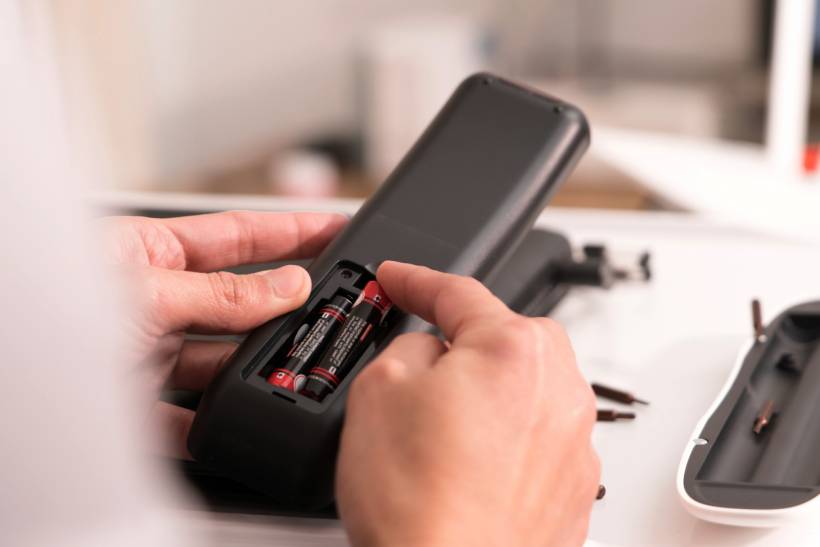 Checking the remote control batteries as part of basic TV repair diagnostics to avoid unnecessary costs