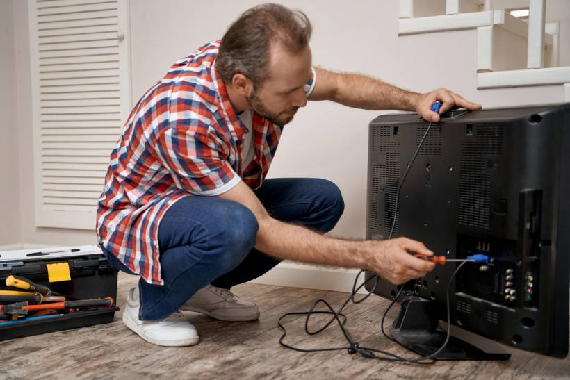 Technician inspecting TV ports, a factor that may influence repair costs