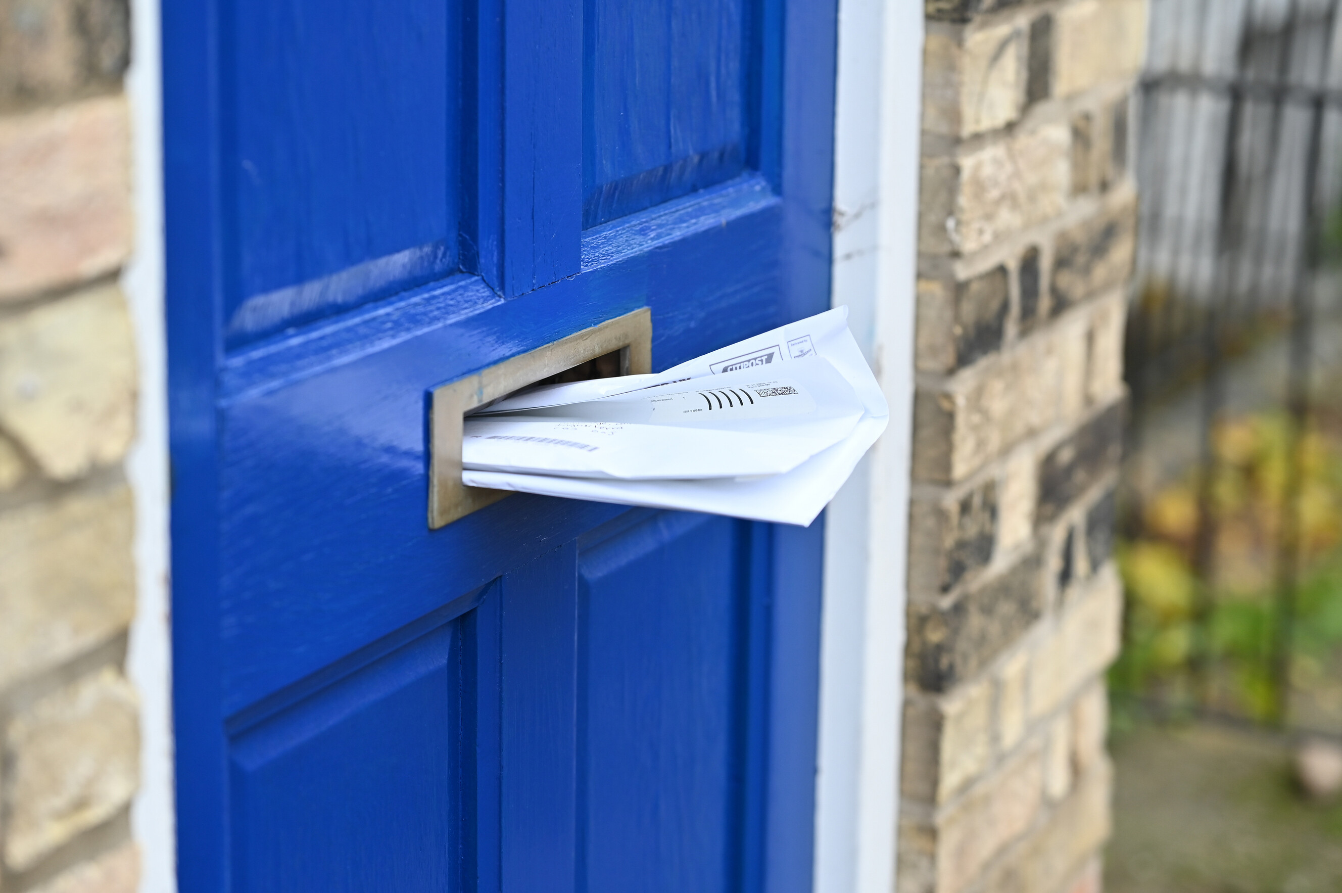 A vibrant blue front door with a white envelope protruding from the mail slot.