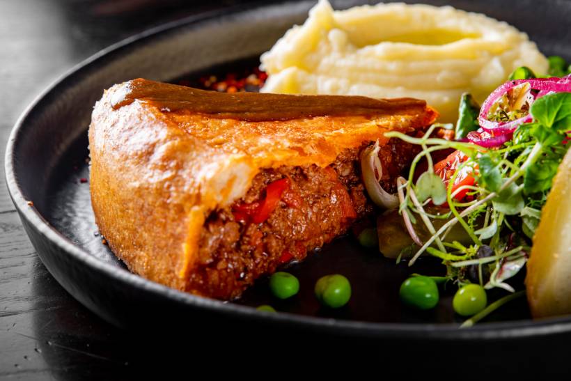 high tea vs afternoon tea - Traditional meat pie filled with ground beef and red peppers, plated with sides for a high tea meal