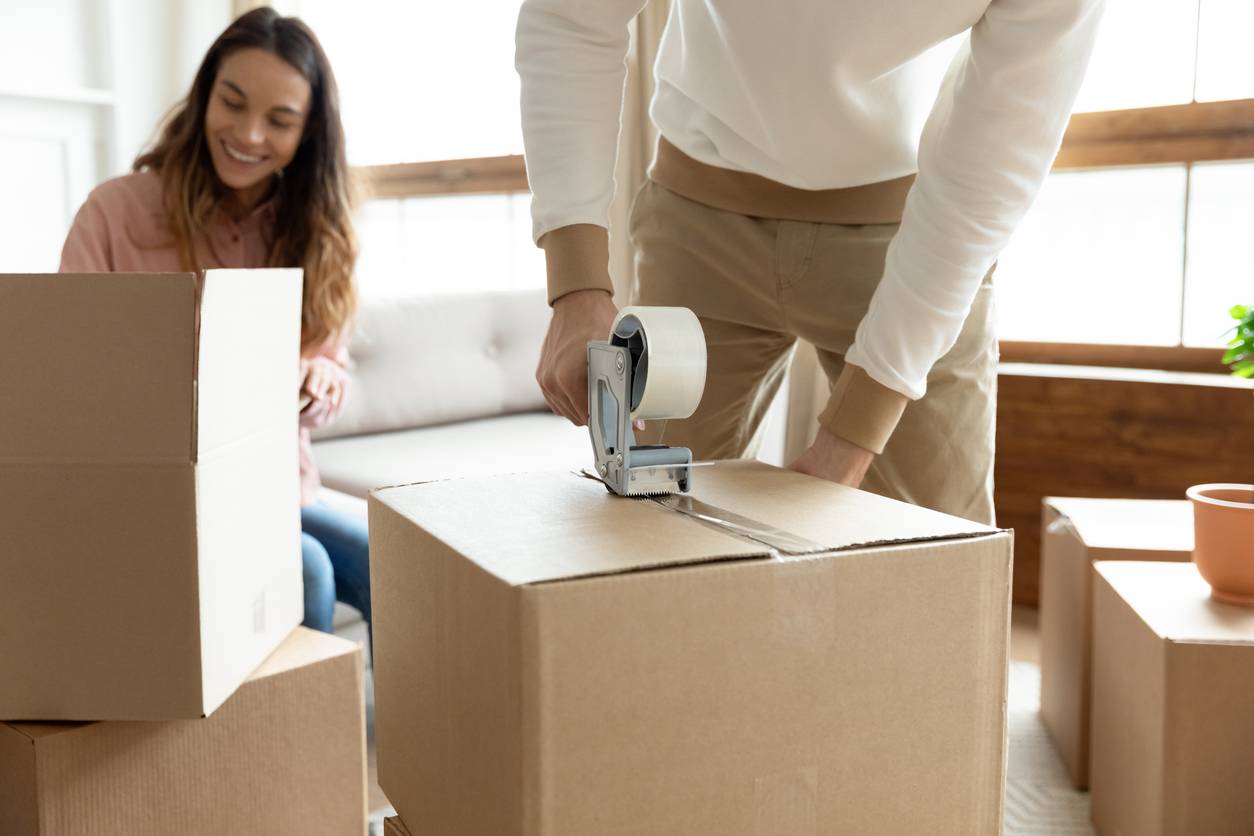 moving to Birmingham - Taping up boxes as a couple begins the moving process in their living space