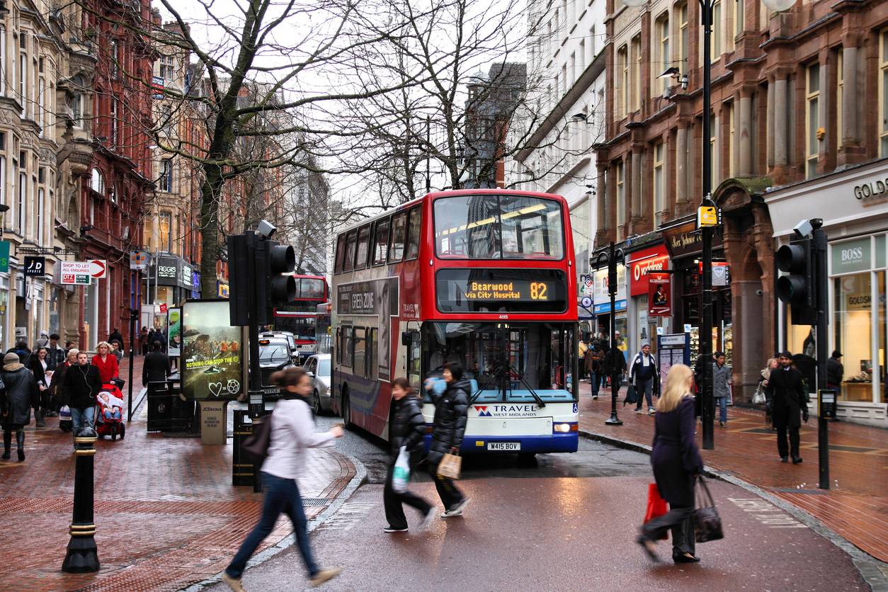 moving to Birmingham - Public transport bus navigating a crowded Birmingham shopping area on a rainy day