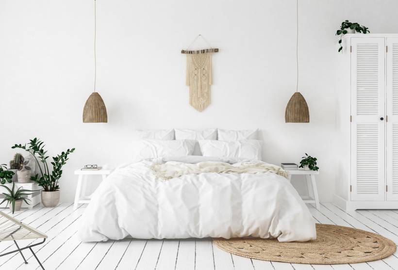 Minimalist bedroom with white walls and bedding, styled in neutral tones and indoor plants, showcasing a possible comparison of Dulux Timeless vs Jasmine White