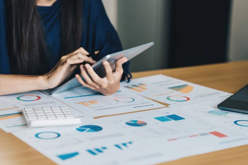 bookkeeper vs accountant - Professional reviewing financial reports and charts on a tablet during account auditing process