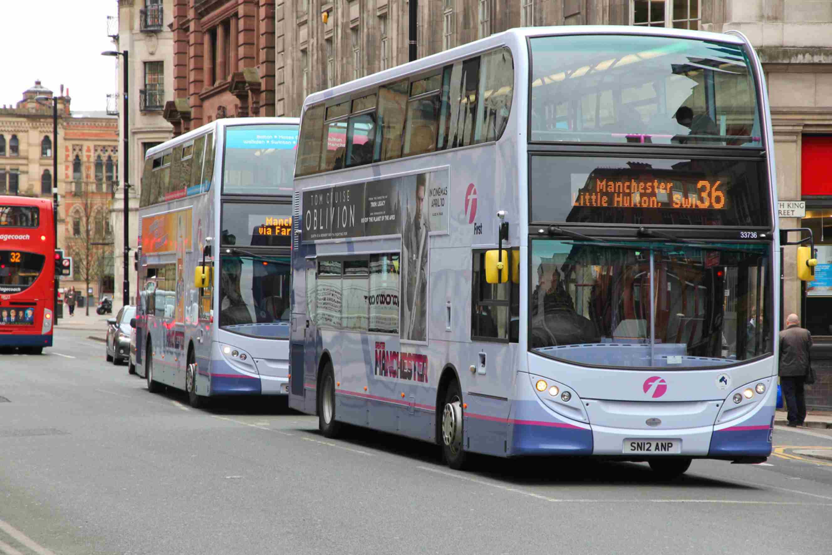 Double-decker buses on a busy Manchester city street, representing a common destination for London to Manchester moves