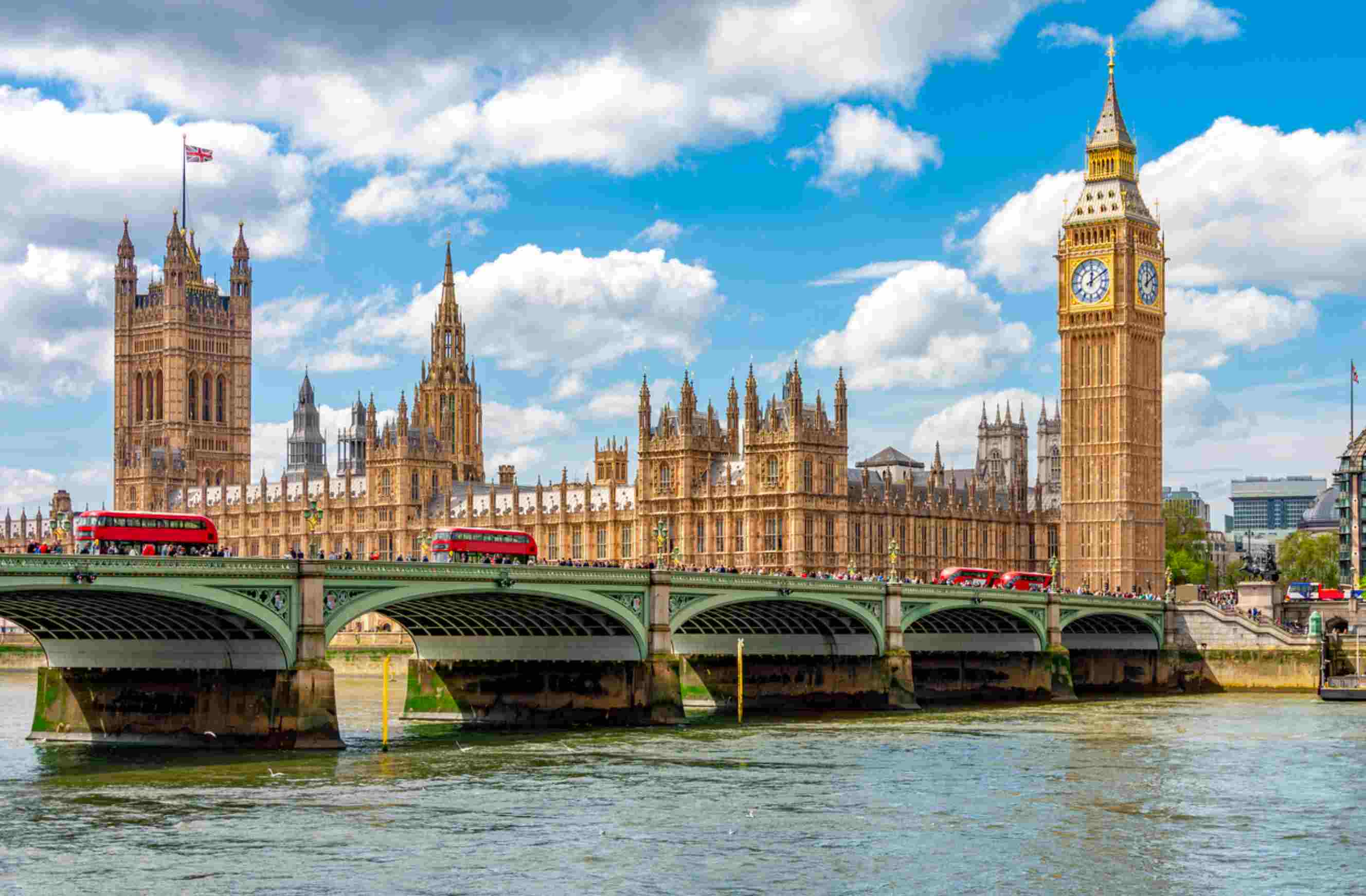 Big Ben, Westminster Bridge and red buses beside the River Thames in London