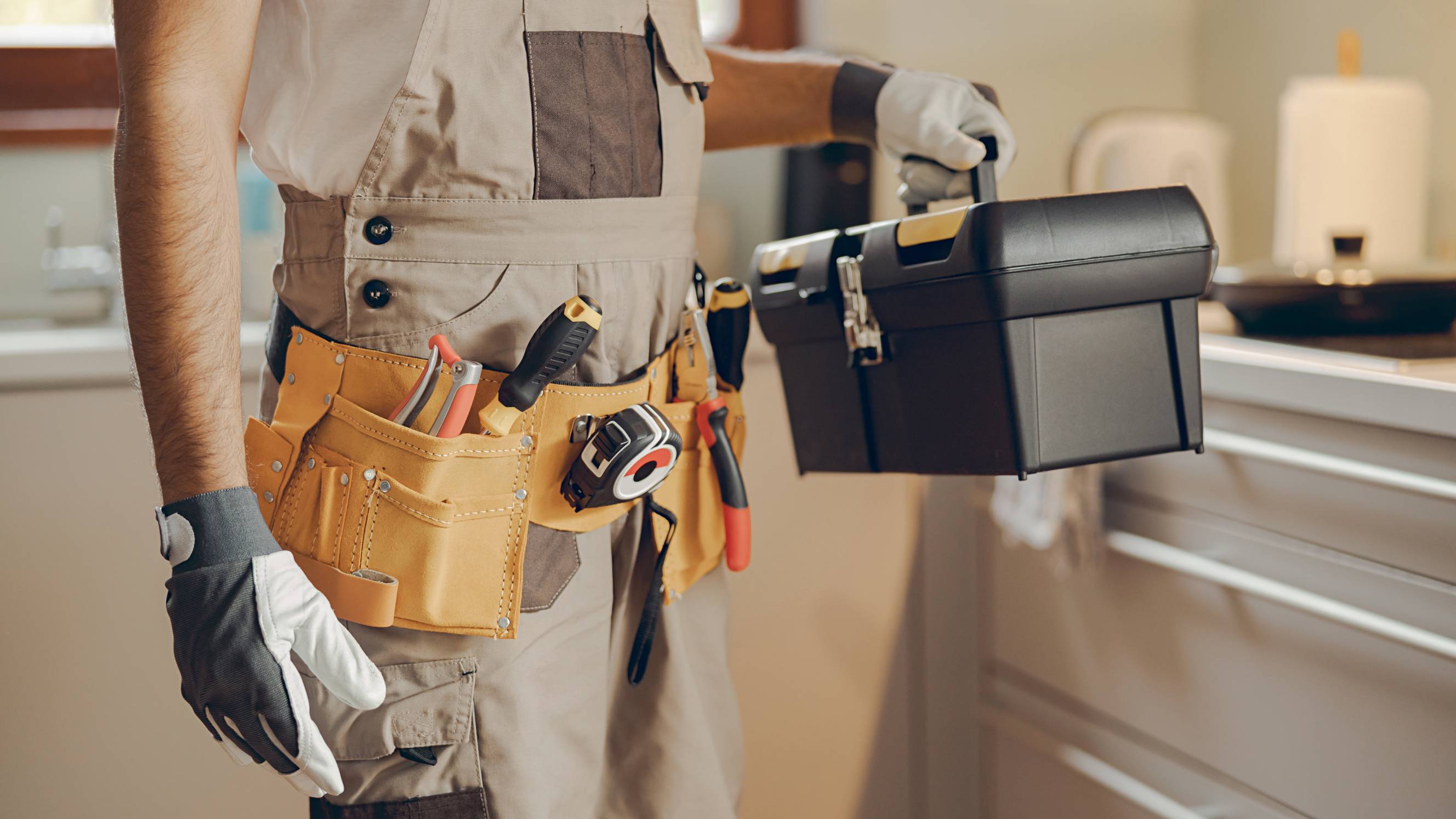 a handyman holding a toolbox in a home kitchen