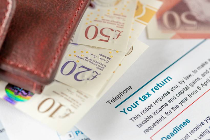 how much does a tax accountant cost - Tax return form with British pound notes and wallet