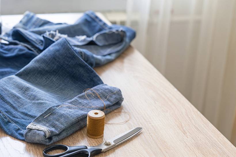 how much does it cost to alter trousers - Denim trousers, sewing scissors, and thread spool for alterations