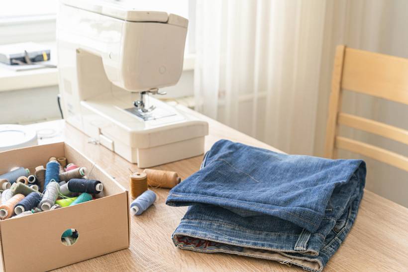 how much does it cost to alter trousers - Denim trousers with sewing machine and assorted thread spools