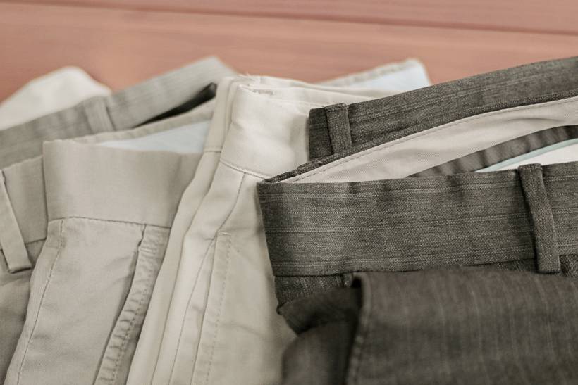 how much does it cost to alter trousers - Assorted dress trousers folded on a wooden surface