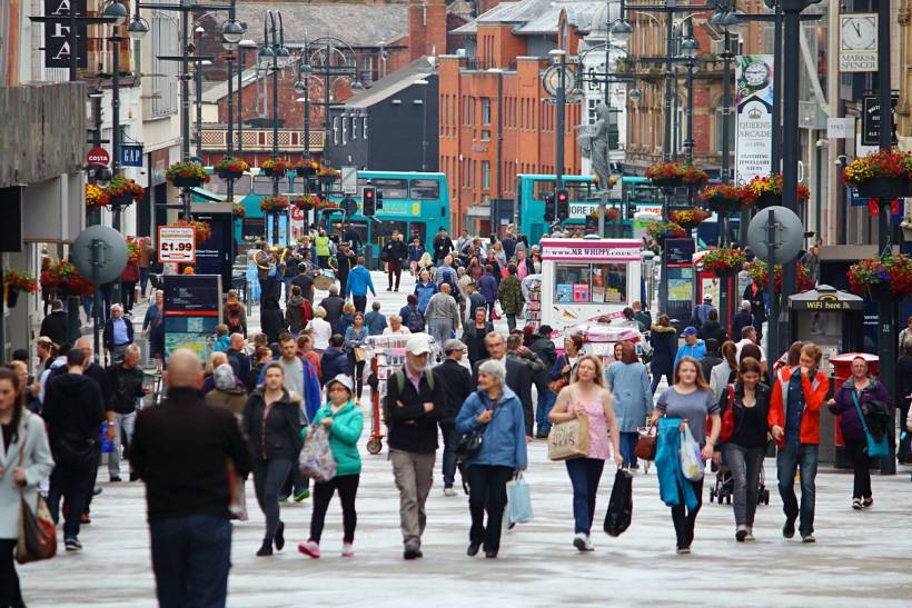 moving to Leeds - Busy pedestrian shopping street with crowds, buses, storefronts and hanging flower baskets