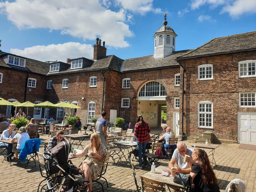 moving to Leeds - Outdoor courtyard café with people seated at tables beside a historic brick building