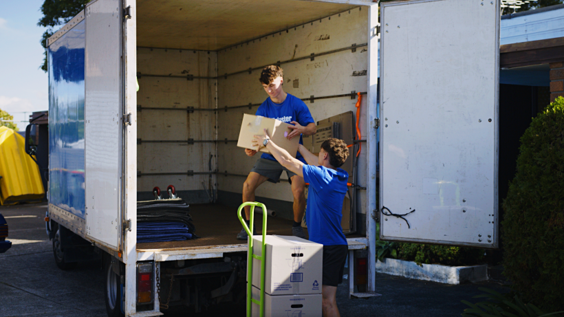 moving to Leeds - Two movers handling packed boxes at the back of a removal van