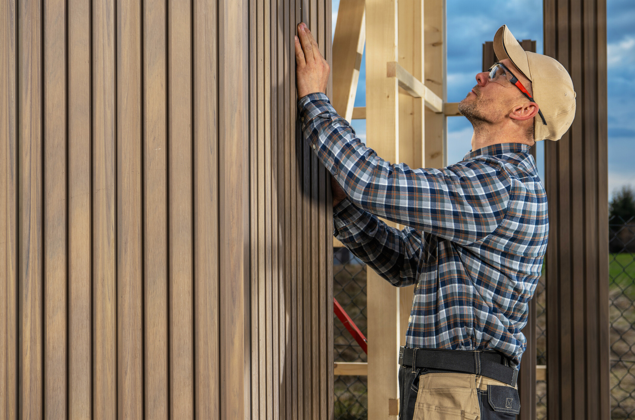 Man aligning vertical wooden wall panels during an outdoor shed installation