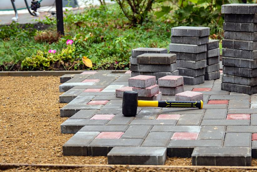 how much does a garden designer cost - Garden pathway construction using concrete paving blocks arranged over a compacted gravel base