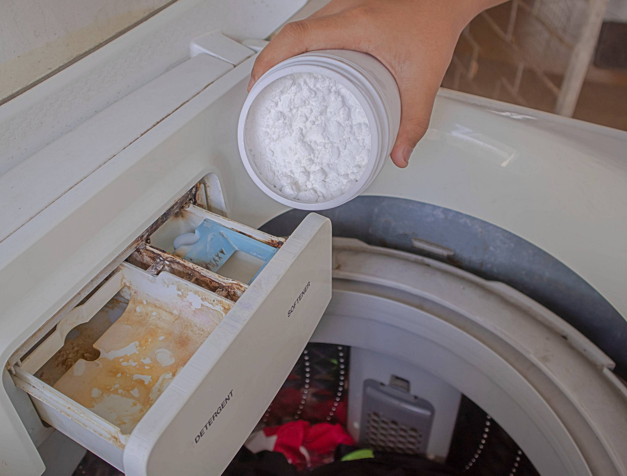 a person using baking soda to clean a washer