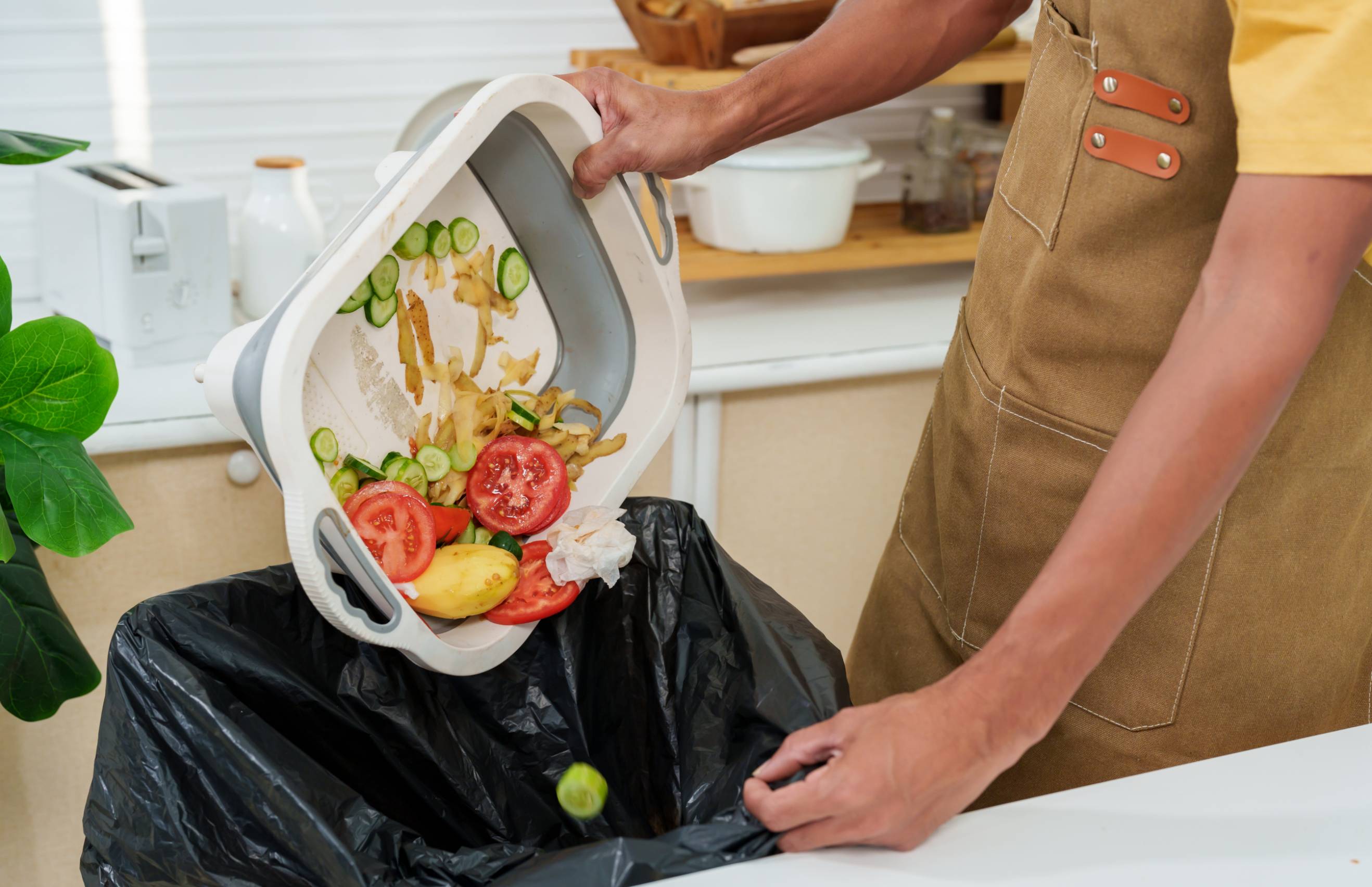 A kitchen waste disposal specialist taking out leftover kitchen waste in a black trash bag