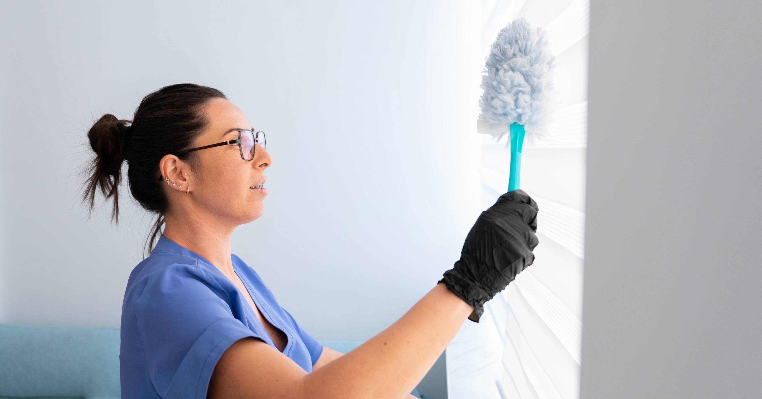 Professional cleaner dusting the the blinds with a duster