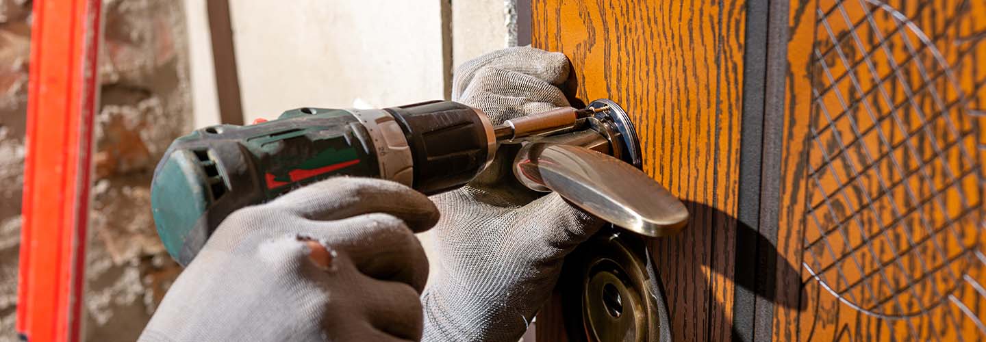 A close-up photo of a hand holding a silver key, ready to replace a lock.