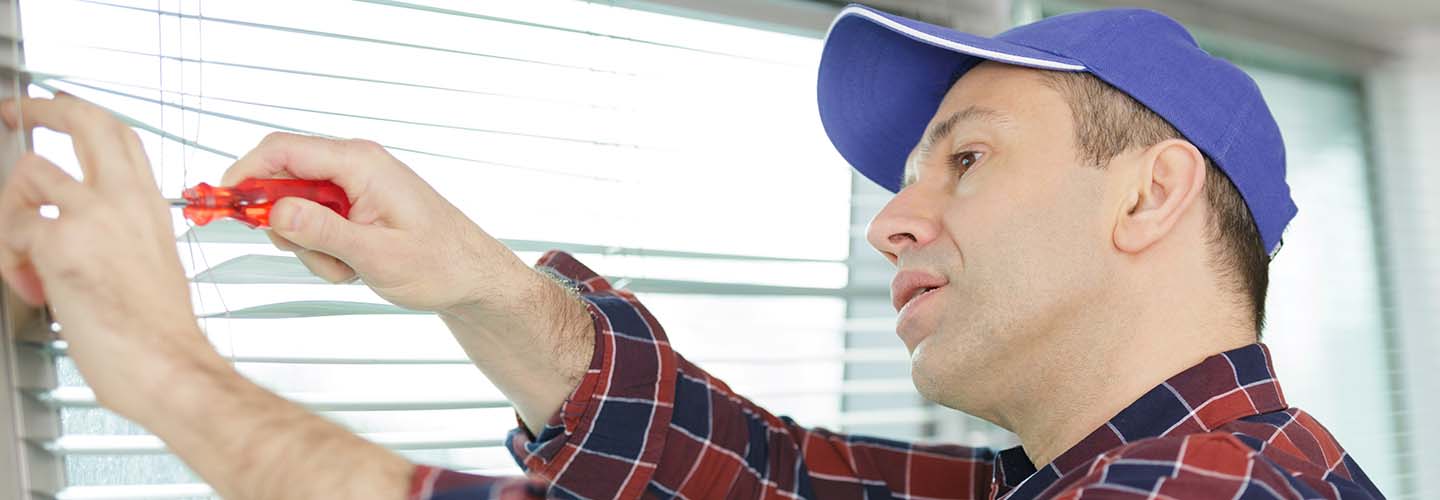 A close-up view of a person repairing a Venetian blind