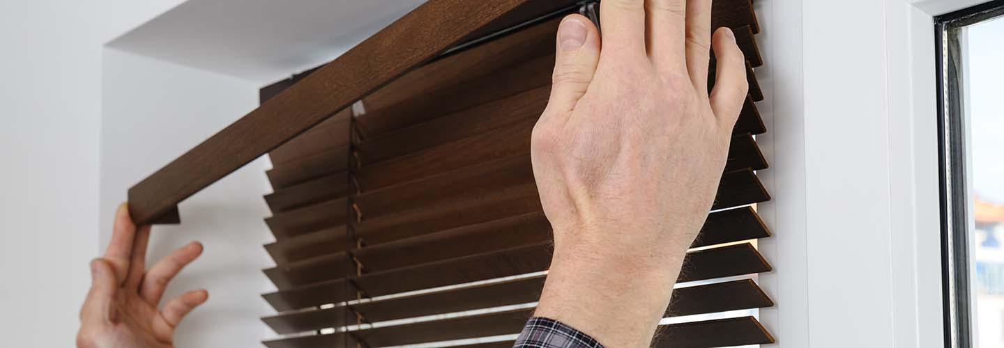 A close-up view of a pair of wooden blinds being installed on a window, adding warmth and style to the room.