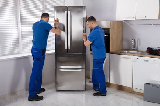 Service providers installing a stainless steel refrigerator 