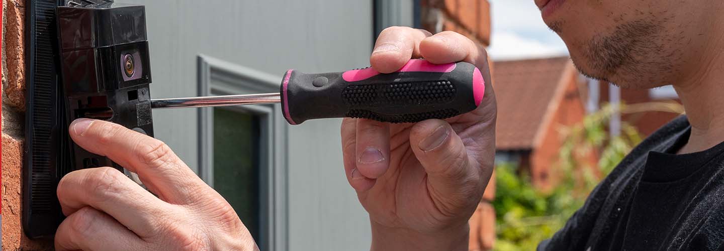 A person installing a Ring doorbell on a front door, using a screwdriver and following the instructions.