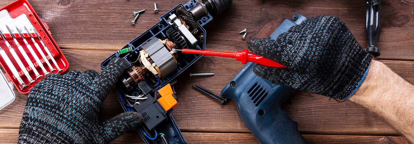 A close-up image of a person repairing a tool with a screwdriver and pliers, showcasing their skilled craftsmanship.